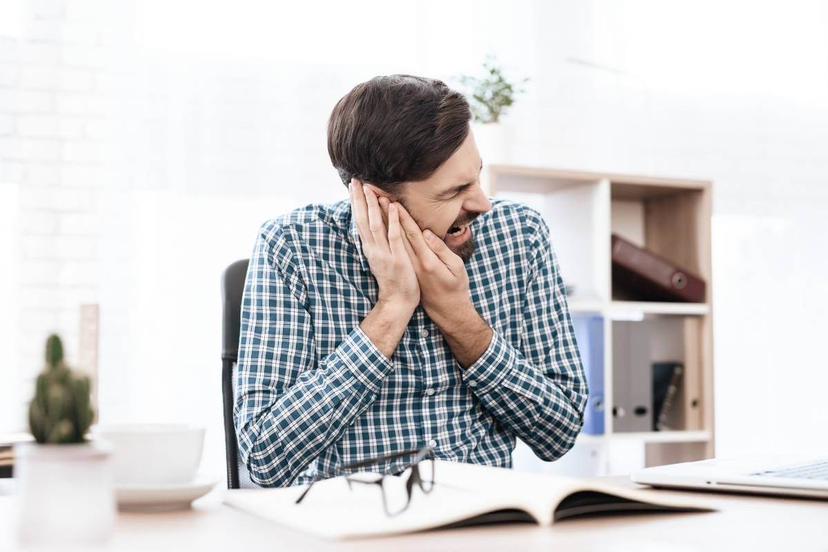 man holding his painful ear in his office