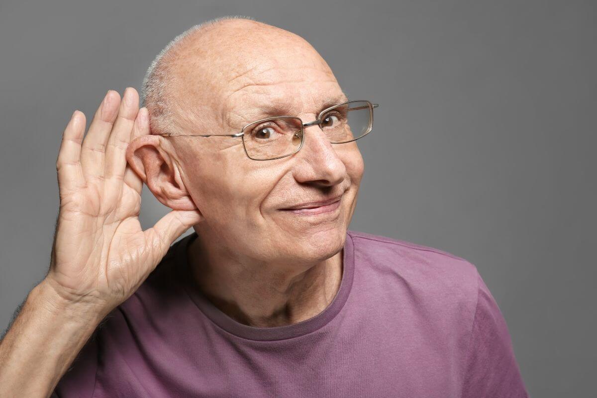 old man with eyeglasses holding his ear to hear better