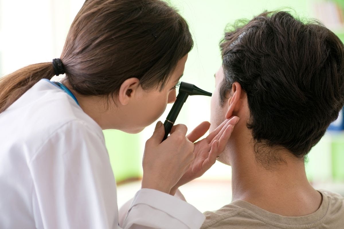 audiologist using an otoscope to examine patient's ear