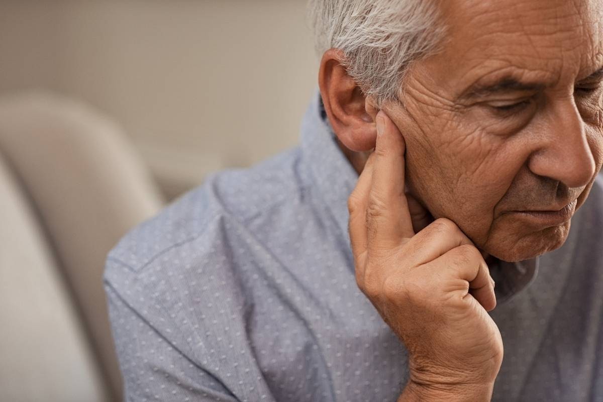 senior man touching his ear to detect ear problems