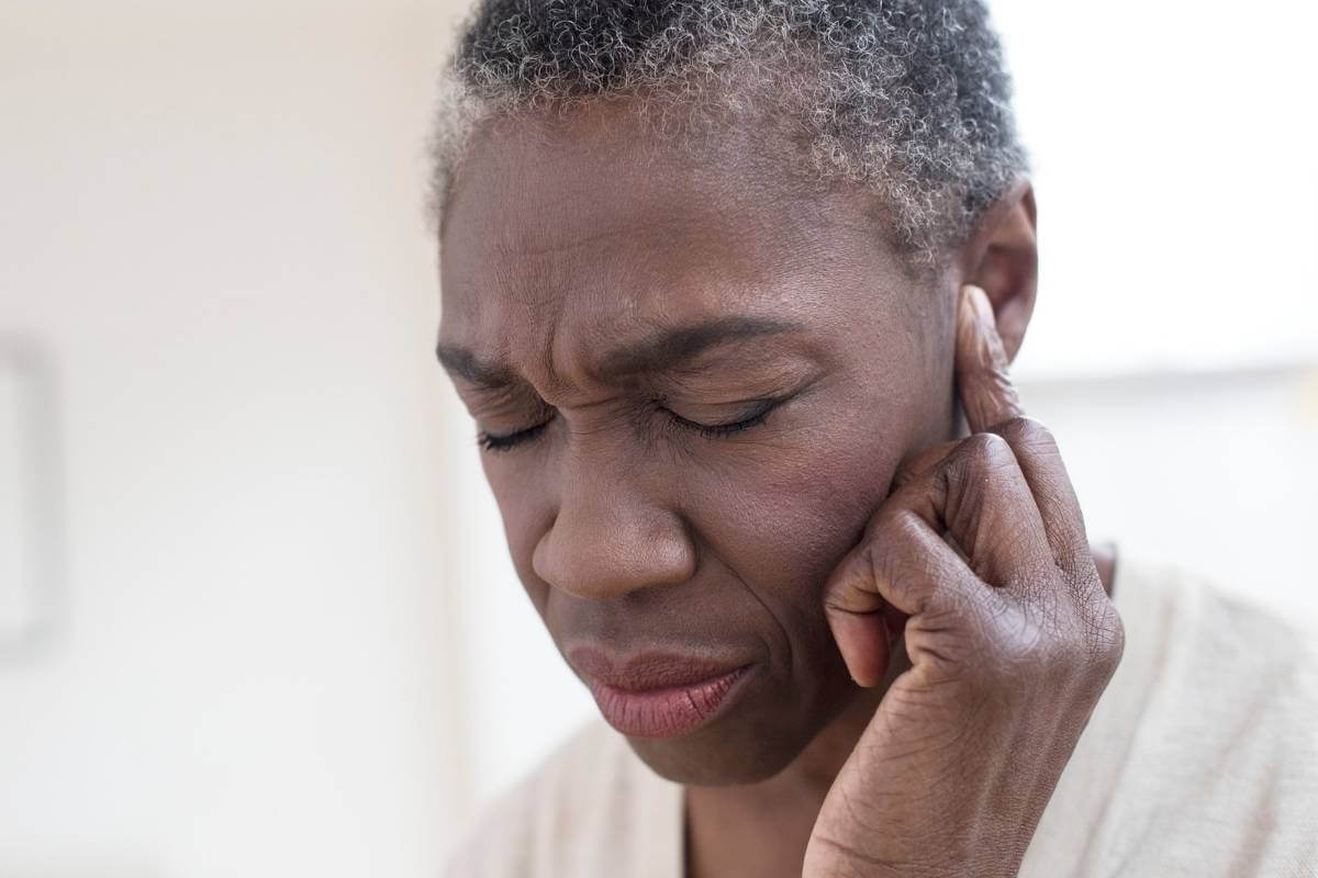 african american woman holding her ear suffering from tinnitus