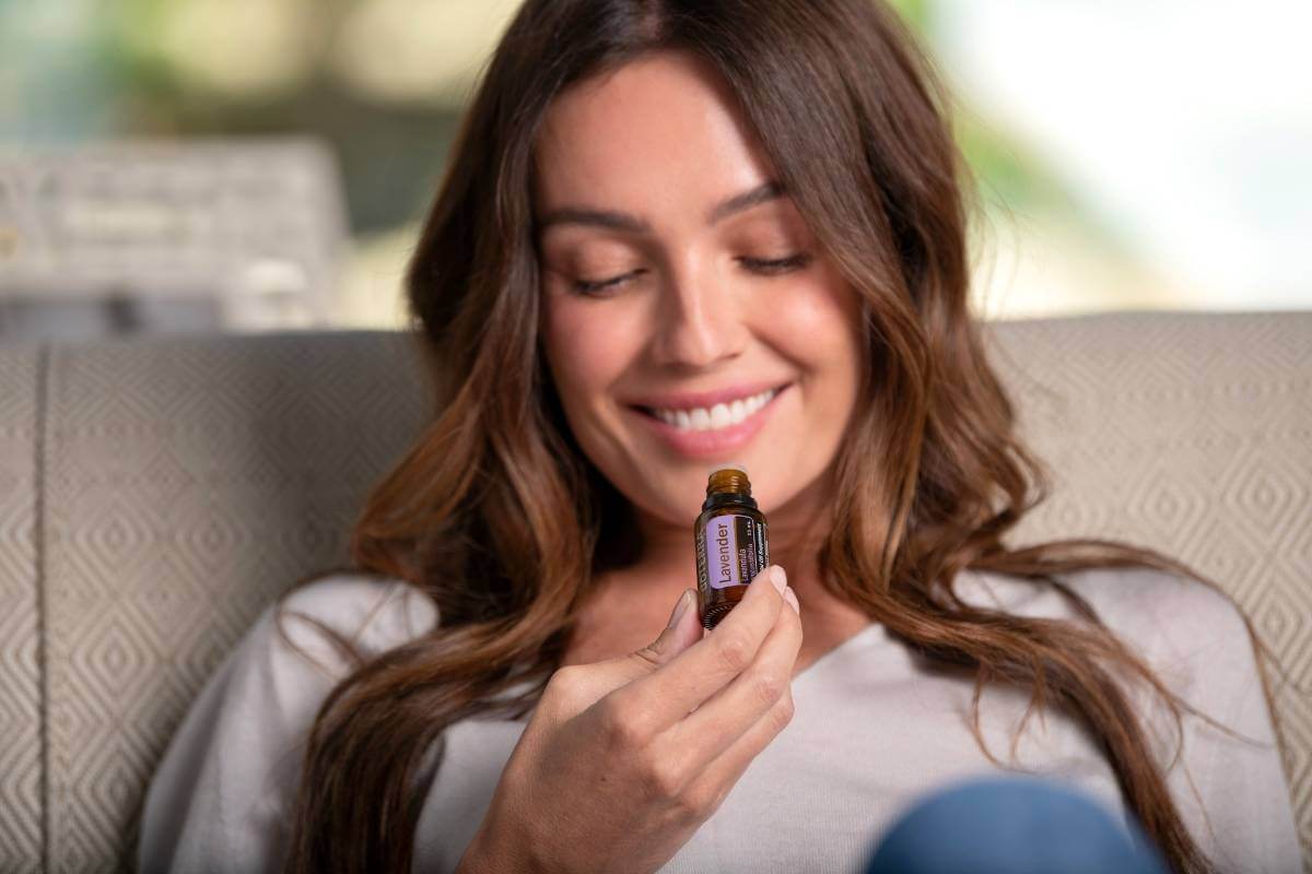 woman smiling and looking at a bottle of lavender essential oil