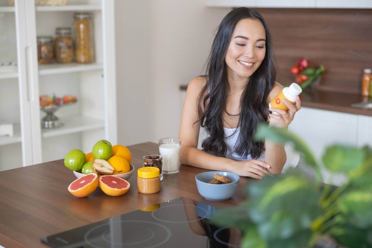 woman reading a supplement bottle in her home kitchen