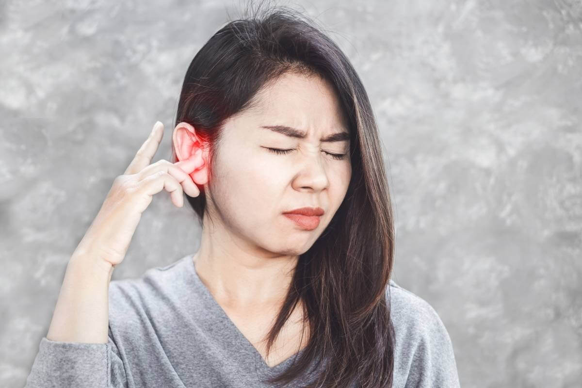 woman in grey sweater having a painful ear