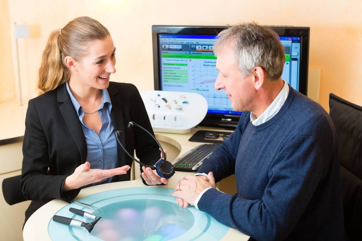 doctor explaining hearing aids to a senior patient